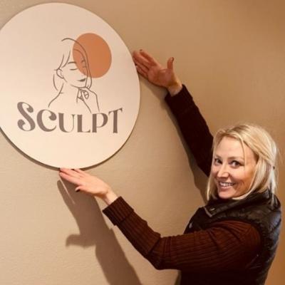 woman pointing to logo for Sculpt hanging on wall